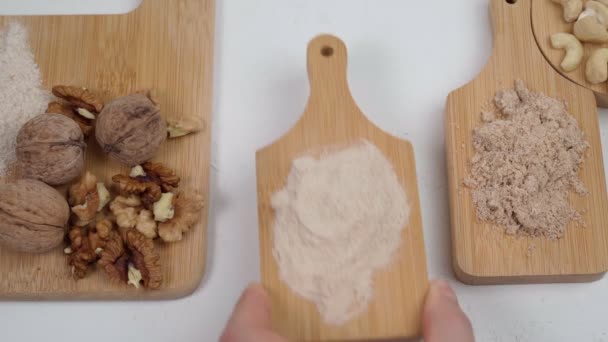 Verschiedenes glutenfreies Mehl auf einem weißen Tisch mit Nüssen. Mandeln, Cashewnüsse, Walnüsse. Flache Lage. — Stockvideo