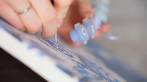 Woman hand holds a brush and paints with paint, painting on an easel draws the details of the picture with paints. Selective focus. — Stock video