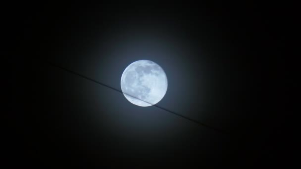 Pełnia księżyca na tle nocnego czarnego nieba, wiszący drut z budynków — Wideo stockowe