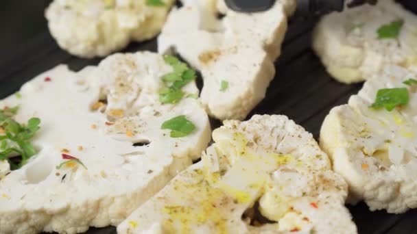 Baked cauliflower steaks with herbs and spices. Healthy vegetarian snack, close up. — Stok video