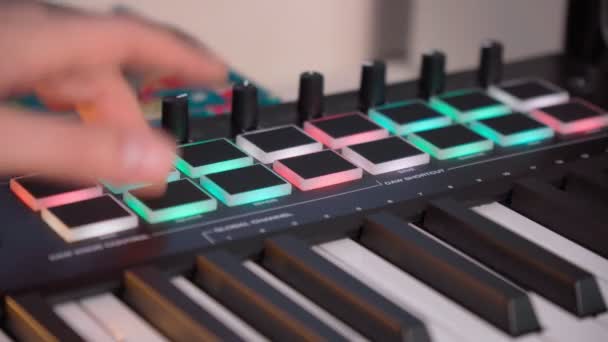 Midi keys on the table with neon lights. Closeup of male hands composing music using midi controller — Stockvideo