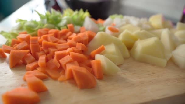Las zanahorias cortadas en cubitos cortaron las papas con cebolla picada en una tabla de cortar. Hortalizas frescas. — Vídeos de Stock