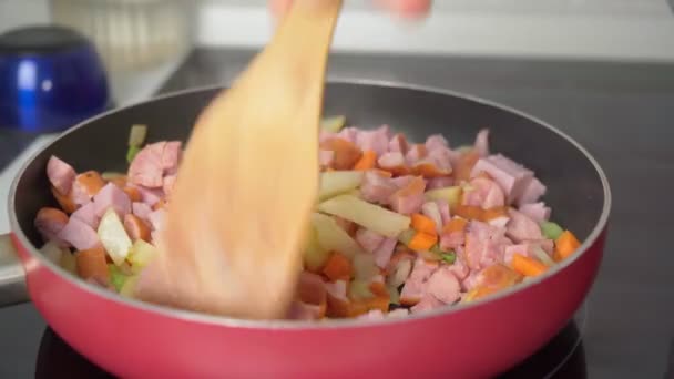 Cooking smoked sausages with vegetables in a frying pan, carrots, potatoes celery — Wideo stockowe