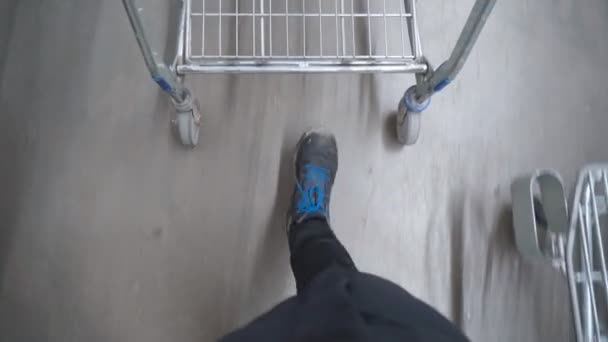 Grocery cart roll through the supermarket, man legs walk through the store. Purchase of goods — Video Stock