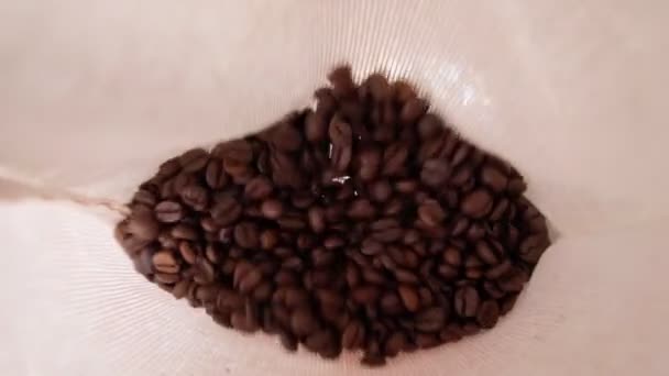 Roasted coffee beans pouring selective focus. Robusta variety inside the cloth bag. Slow motion — Stockvideo