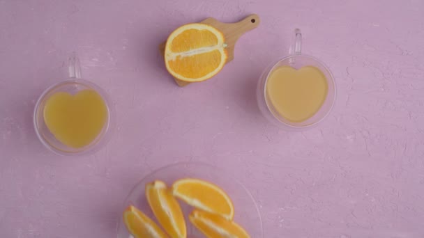 Szklanka soku pomarańczowego z pomarańczami widok z góry, amaranth różowe tło. Leżeć płasko. Miłość do owoców, zdrowa żywność — Wideo stockowe