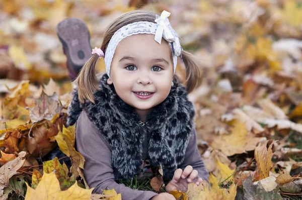 Adorable petite fille avec des feuilles d'automne dans le parc de beauté — Photo