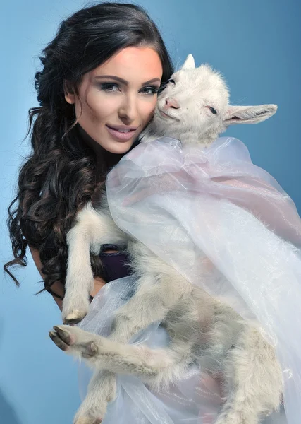 Brune mignonne tenant une petite chèvre — Photo