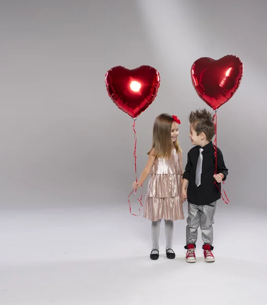 Happy kids with red heart balloon on a light background — Stock Photo, Image