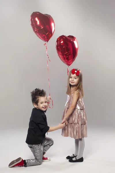Niños felices con globo de corazón rojo sobre un fondo claro — Foto de Stock