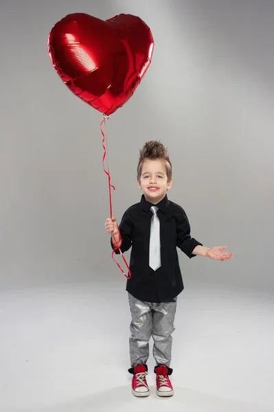 Hafif bir arka plan üzerinde kırmızı kalp balon ile mutlu küçük çocuk — Stok fotoğraf