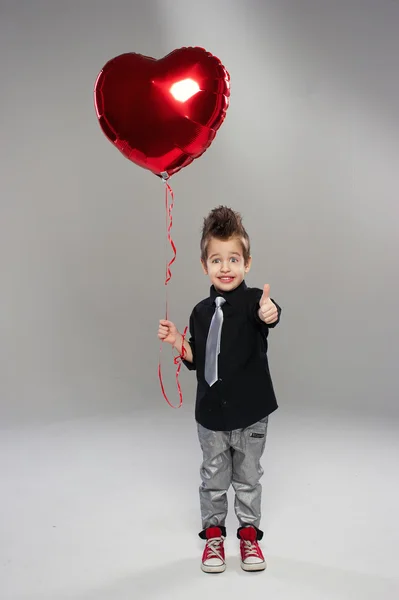 เด็กน้อยที่มีความสุขกับลูกโป่งหัวใจสีแดงบนพื้นหลังที่สว่าง — ภาพถ่ายสต็อก
