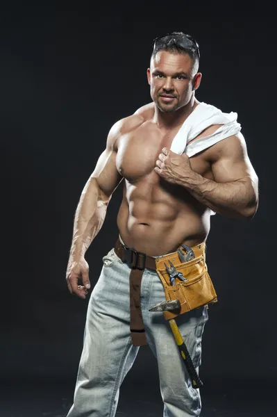 Image of young handsome builder posing, on dark background — Stock Photo, Image