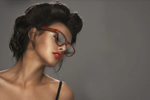 Fashion portrait of a beautiful brunette woman with shot hairstyle with orange sunglasses - studio photo — Stock Photo, Image
