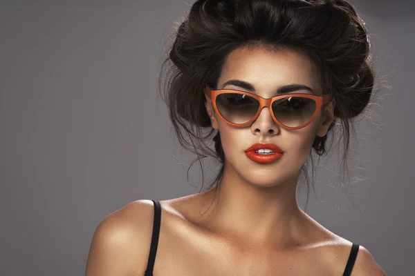 Modeporträt einer schönen brünetten Frau mit Schnapsfrisur und orangefarbener Sonnenbrille - Studiofoto — Stockfoto