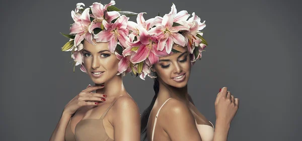 Две красотки улыбающиеся девушки с цветами в волосах — стоковое фото