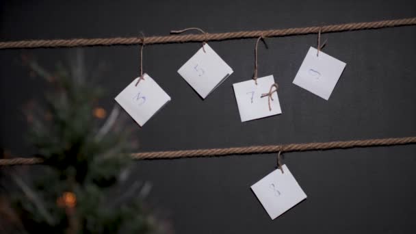 自制的Diy日历 用黑色背景做的 用手工操作的绳子捆扎 前景是一棵有花环的圣诞树 男性的手绑着另一个标签 — 图库视频影像