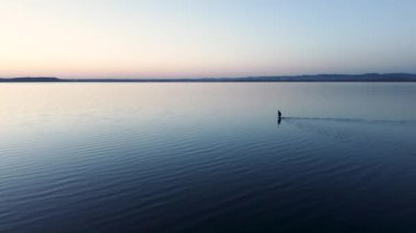 Sakin bir deniz, sığ sularda kıyı şeridinden uzakta, gün batımından önce serin bir sonbahar akşamı. Kamera sabit.