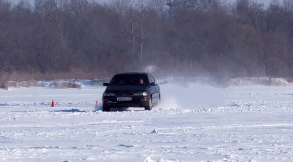 1月22日 2022年1月22日 俄罗斯普里莫尔斯基边疆区的Spassk Dalniy 一辆黑色轿车在冰雪覆盖的公路上行驶 车尾是树木 从右到左 阳光灿烂 — 图库照片