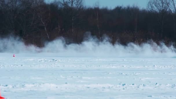 ロシア プリモルスキー地方のSpassk Dalny 2022年1月22日 左から右 晴れた日 スローモーションの木の背景を背景に 凍結した湖の雪に覆われた高速道路に沿って黒い車が運転する — ストック動画
