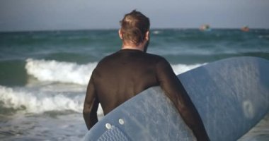 Emekli bir sporcu denize girer, dalgalarda sörf yapmaya gider. Sahilde sörf tahtası taşıyan yakışıklı bir sporcunun portresi..