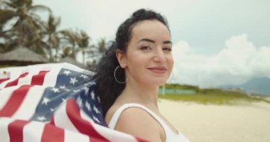 Vatanseverlik, bağımsızlık günü ve tatil konsepti. Yaz mevsiminde ulusal Amerikan bayrağıyla mayolu mutlu bir genç kadın..