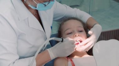 Diş hekimliği, kadın diş hekimi klinikteki küçük kız çocuğuna diş tedavisi. Kadın profesyonel doktor Stomatolog iş başında. Konsept Diş Denetimi.