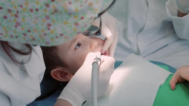 Dentista profissional no trabalho. Dentista no consultório odontológico, mulher dentista trata os dentes para um menino paciente na clínica. Conceito de exame dentário. — Vídeo de Stock