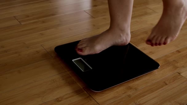 여자들은 비늘의 무게를 재고 있습니다. 여자들은 비늘에 발을 딛고 있습니다. 여자들의 다리는 방 안에서 저울 위에 서 있습니다. 여자발은 BMI 체중 감량을 확인 합니다. 비대 한 사람 의체중 과다 지방 — 비디오