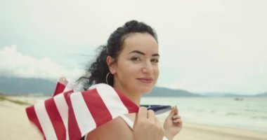 Vatanseverlik, bağımsızlık günü ve tatil konsepti. Yaz mevsiminde ulusal Amerikan bayrağıyla mayolu mutlu bir genç kadın..