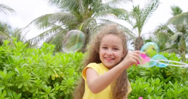 Портрет смішної милої дівчинки, що дме мильні бульбашки . — стокове відео