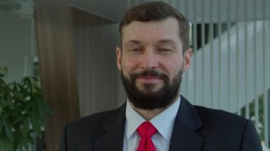 Yakışıklı üst düzey yönetici kameraya bakıyor. Modern şirket ofisinde yakışıklı beyaz adam takım lideri, gülümseyen etnik sakallı girişimci ya da yönetici.