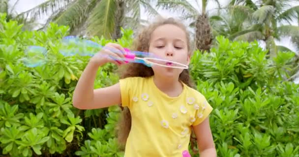 Schattig blank kind, kind dat graag zeepbellen blaast in een park. close-up klein meisje gelukkig genieten en het maken van zeepbellen. — Stockvideo