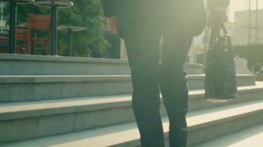 İş yerine gitmek için merdivenlerden koşarak çıkan, acele eden, orta yaşlı bir işadamının yakın çekimi. İş adamının işe gidiş gelişinin arkası..