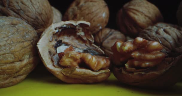 Close-up Shot walnoten die op een gele tafel tegen een zwarte achtergrond liggen. Close-up camera reist langs de liggende moeren zo dicht mogelijk bij de gehakte walnoot. — Stockvideo