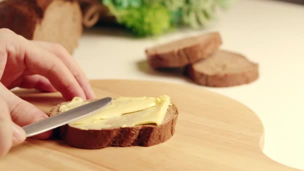 Brzy ráno žena připraví pro svou rodinu sendvič, namaže organické máslo na chleba. Jemné máslo naneste na kousek chleba. Sacharidy, tuková koncepce — Stock video