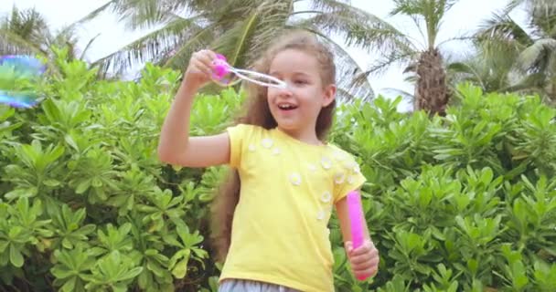 Söt kaukasisk grabb, barn som glatt blåser såpbubblor i en park. Närbild liten flicka glatt njuter och göra såpbubblor. — Stockvideo
