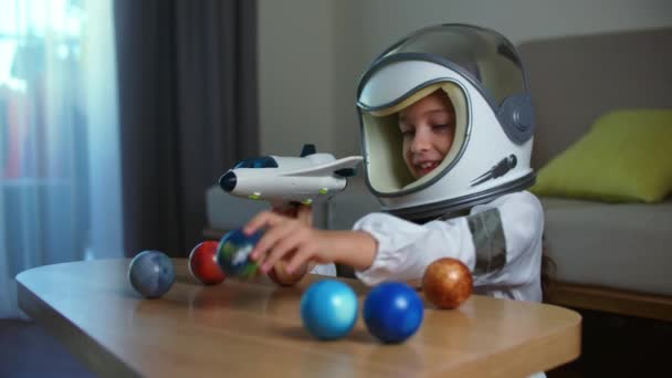 Дитина грає вдома в космонавті, кумедний портрет маленької дівчинки віком 8-9 років в іграшковому костюмі, усміхнена дитина, запускає космічну ракету, крупним планом, пілот, що подорожує в космосі. Щасливе дитинство — стокове відео