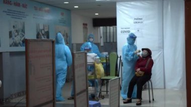 Ho Chi minh, Vietnam -21 Eylül 2021: Koruyucu kıyafetli bir doktor olası bir koronavirüs COVID 19 testinden boğaz ve burun çubuğu alıyor.