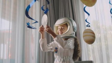Fantezi çocuk astronot askıya alınmış kozmik gezegenlerle oynuyor. Yaban arısı astronot kostümlü kız astronot çocuk odasında bir odada oynuyor. İç mekan gezegenlerle dolu..
