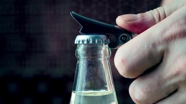 Рука чоловіка відкриває пляшку мінеральної води з відкривачем пляшок на внутрішній кухні. Повільний рух — стокове відео