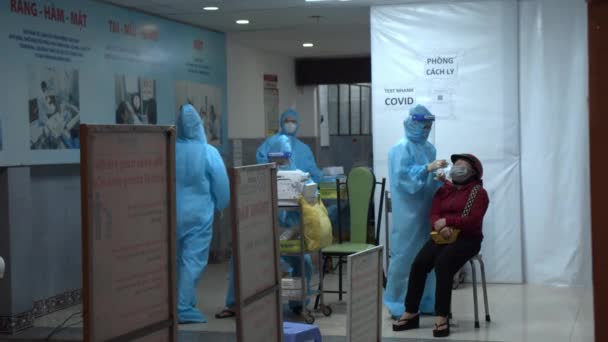 Ho Chi minh, Vietnã - 21 de setembro de 2021: Um médico de terno protetor que toma um cotonete e cotonete nasal de um possível coronavírus COVID 19 teste para pessoas. — Vídeo de Stock