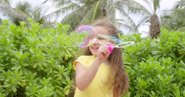Portré vicces szép kislány fúj szappanbuborékok. — Stock videók