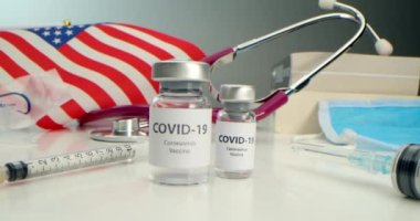 COVID-19 aşısı geliştirildi, koronavirüs aşısı ampulü ve çeşitli şırıngalar, tıbbi aletler, yüz kalkanı, Amerikan bayrağı geçmişi ve kitapları geliştirildi..