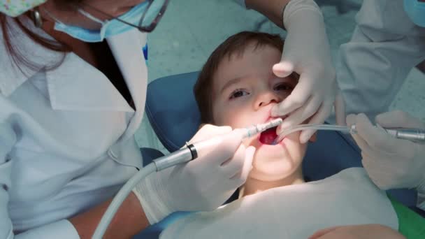 Dentystka w gabinecie stomatologicznym, dentystka lecząca zęby małemu chłopcu pacjentowi w klinice. Kobieta Lekarz Stomatolog w pracy. Koncepcja badania stomatologicznego. — Wideo stockowe