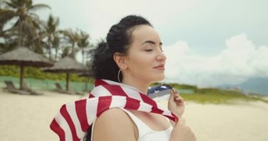 Vatanseverlik, bağımsızlık günü ve tatil konsepti. Yaz mevsiminde ulusal Amerikan bayrağıyla mayolu mutlu bir genç kadın..