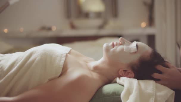 Wanita muda Kaukasia yang cantik berbaring di tempat tidur spa menerima pijat bibir dengan perawatan kulit dengan minyak esensial aromatik dari seorang tukang pijat di salon kecantikan. Kesehatan Kesejahteraan perawatan tubuh Pijat spa konsep. — Stok Video