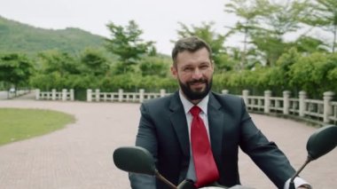 Yaşlı sakallı, gülümseyen bir iş adamının portresi cadde boyunca motosikletle geliyor. Yakışıklı, yaşlı, mutlu bir iş adamının portresi..