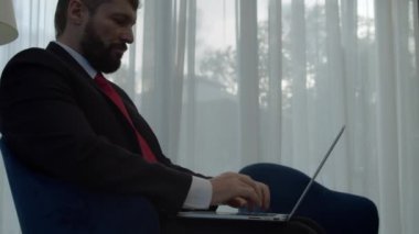 Ofis lobisinde dizüstü bilgisayarla çalışan ciddi sakallı bir iş adamı. Ofiste dizüstü bilgisayarda daktilo kullanan profesyonel bir erkek. Portre pozitif iş adamı dizüstü bilgisayarı içeride görüyor