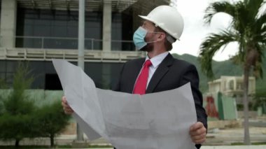 Mühendis Planlama Üretim yüz maskesi ve ayrıntılı bir taslak. Koruyucu Hardhat Giyen Erkek Teftiş Birimi Koruyucu Maske Virüsü COVID 19 salgın ya da salgın hastalıkla karşı karşıya.